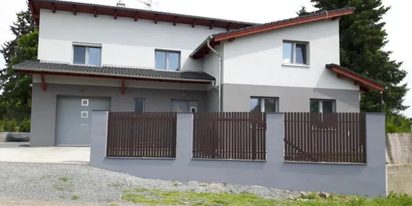 Moderní rodinný dům s tmavým laťovým plotem a bránou